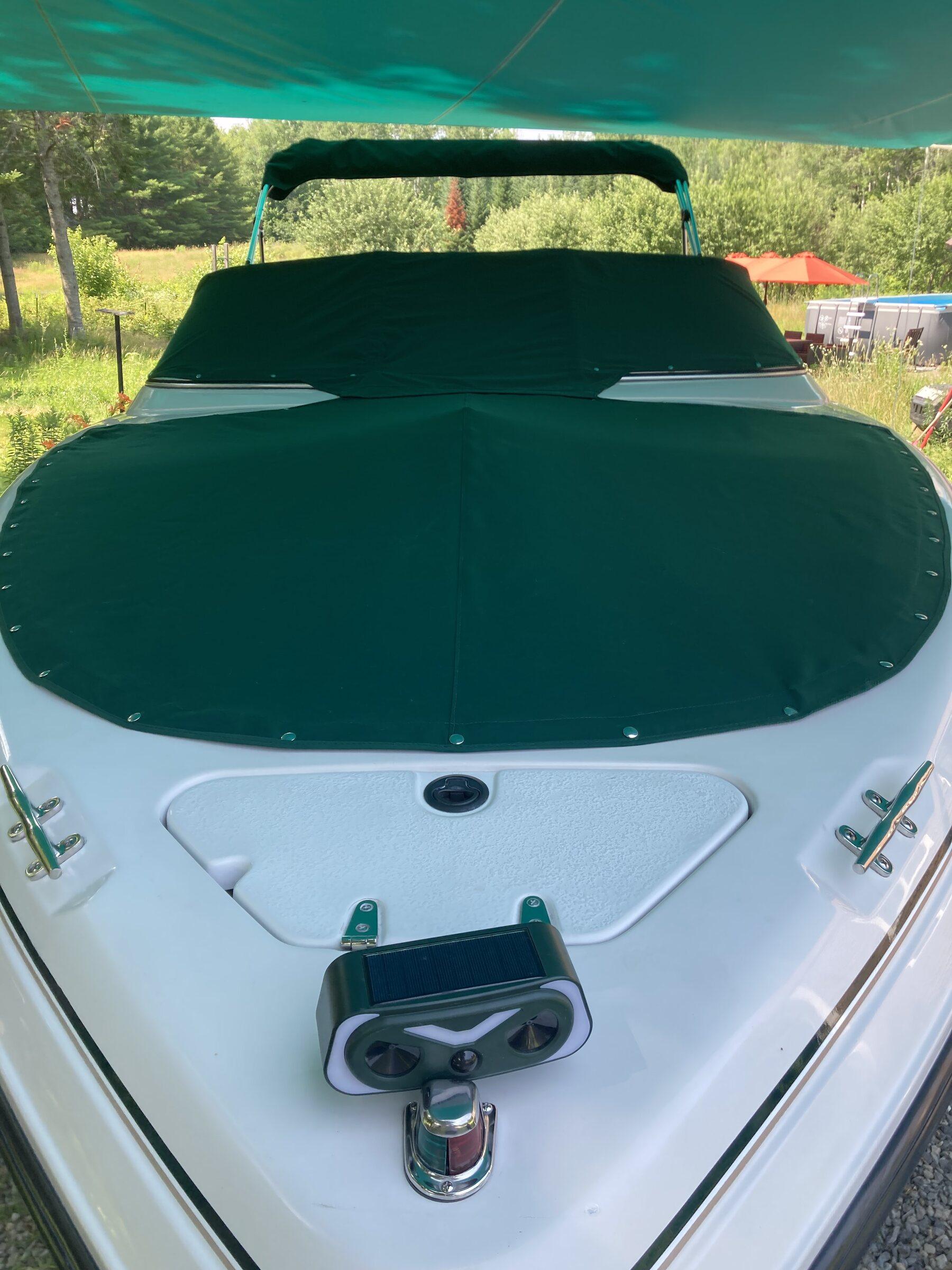 Custom green fitted boat cover secured across the bow